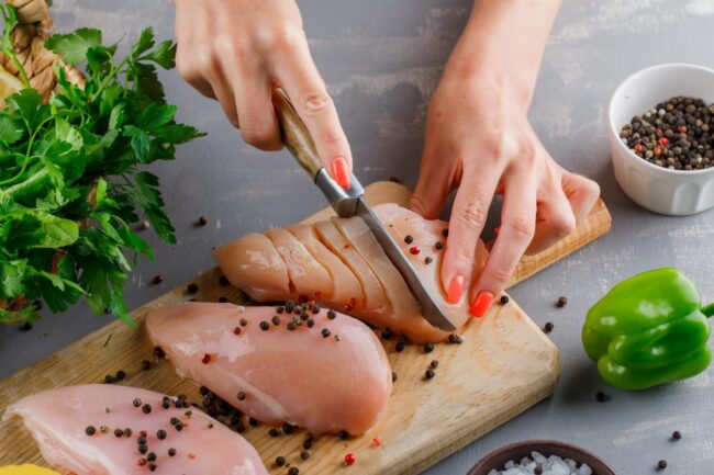 Photo of person cutting chicken illustrates blog: What Is Chicken Pizzaiola?