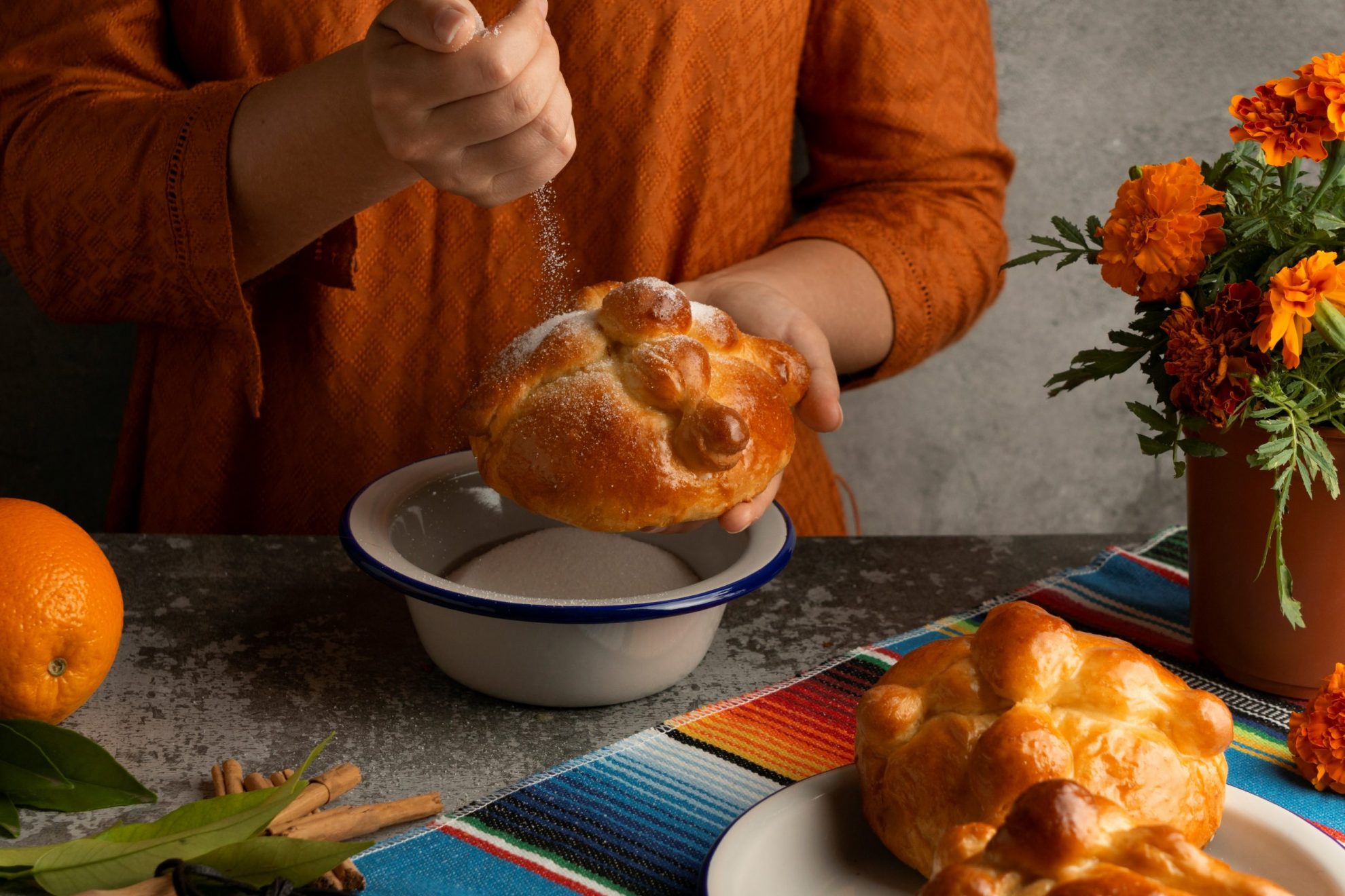 Image of person holding pan de muerto illustrates blog "4 Spooky Dishes to Celebrate Halloween"