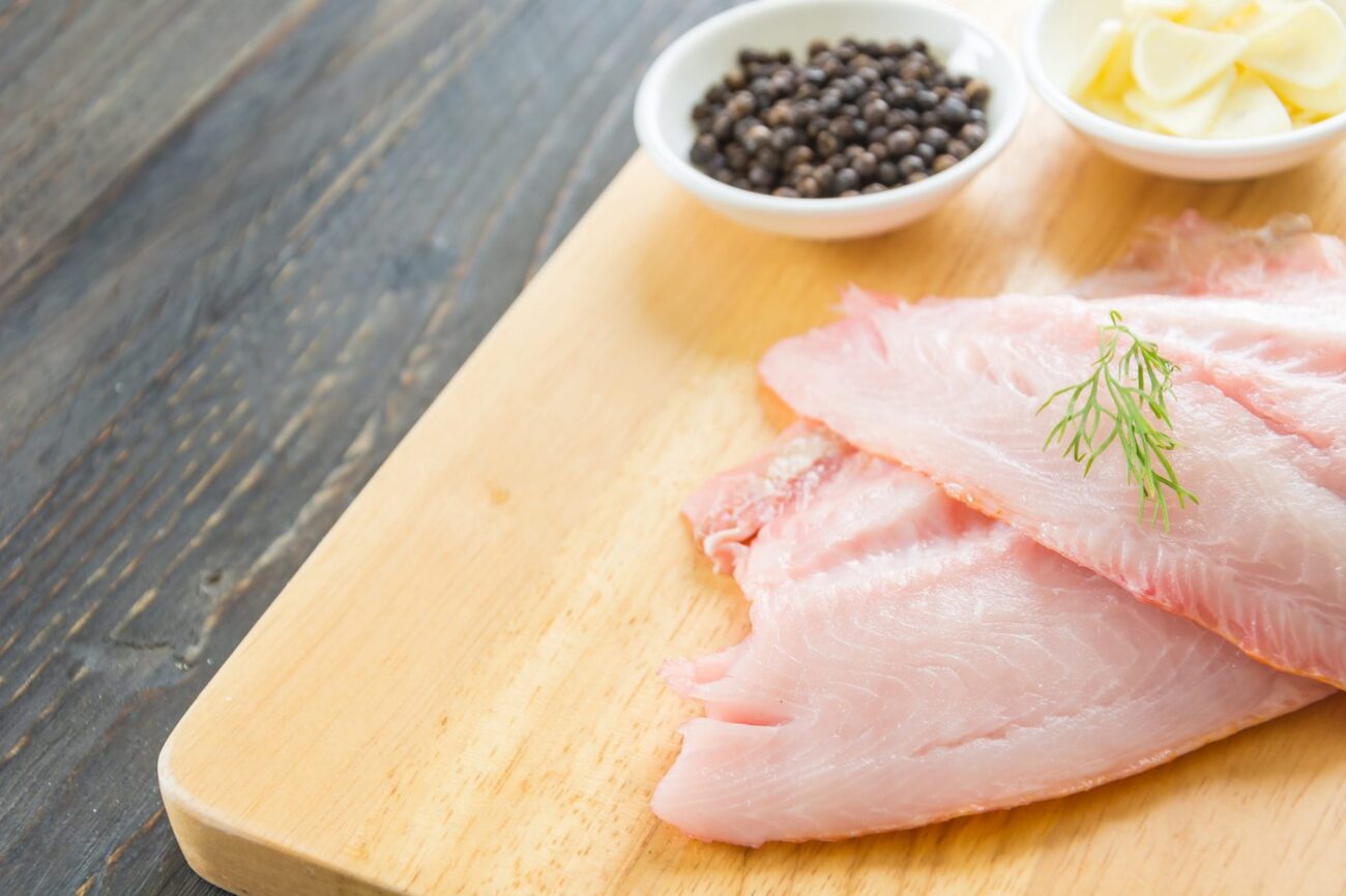 Photo of tilapia on cutting board illustrates blog:; "How To Tell if Tilapia Is Spoiled"