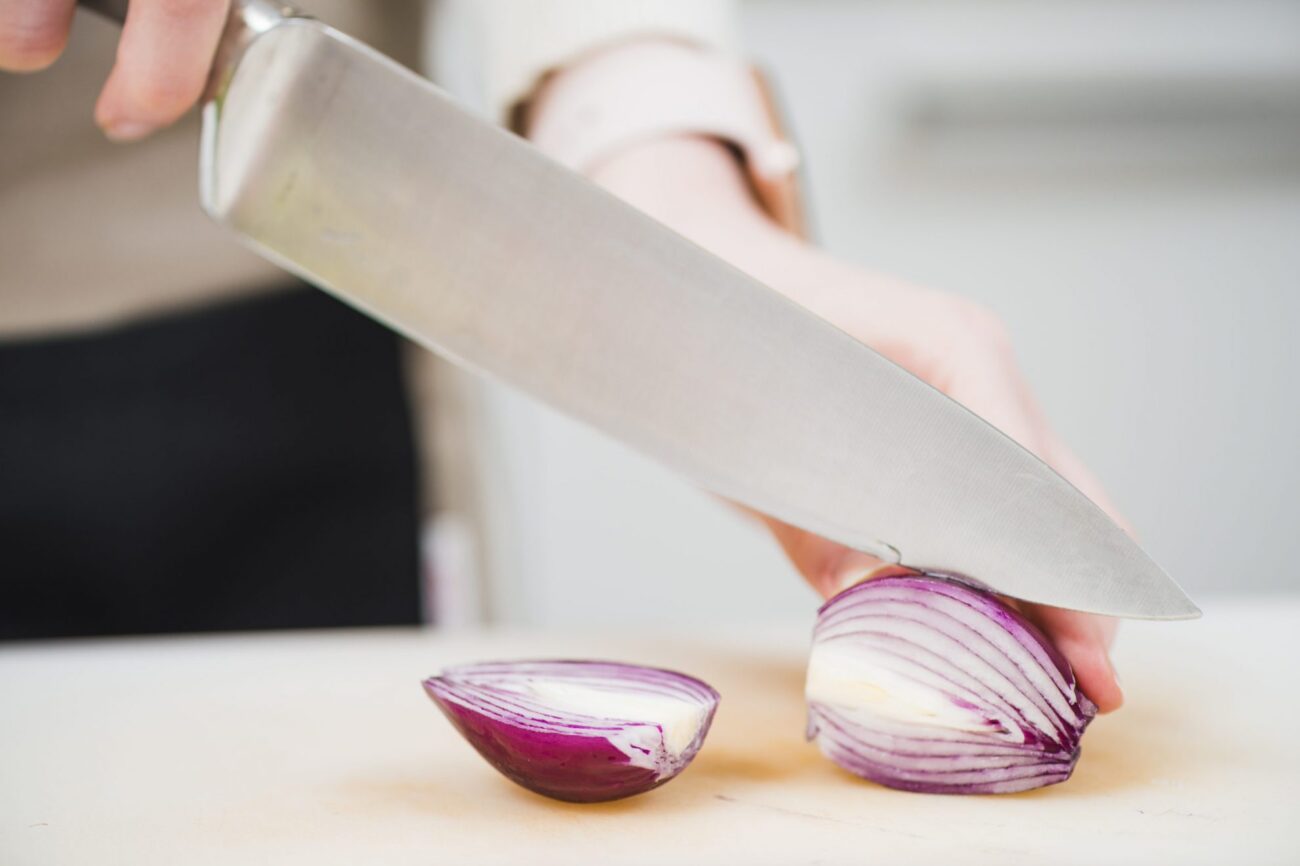Photo of person slicing onions with kitchen knife"