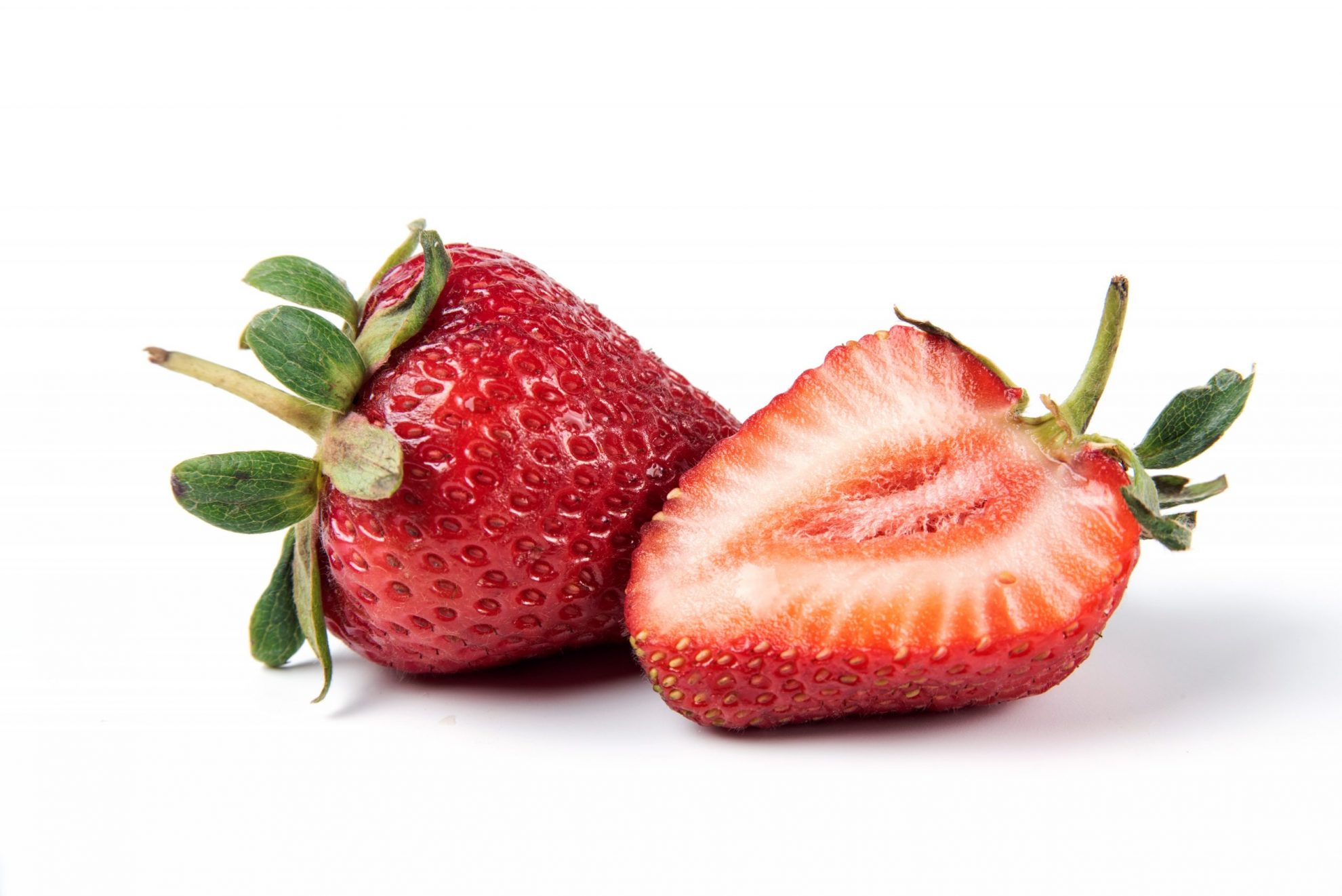 Two strawberries, one whole and one cut in half, illustrate blog "Will Strawberries Ripen in the Fridge?"