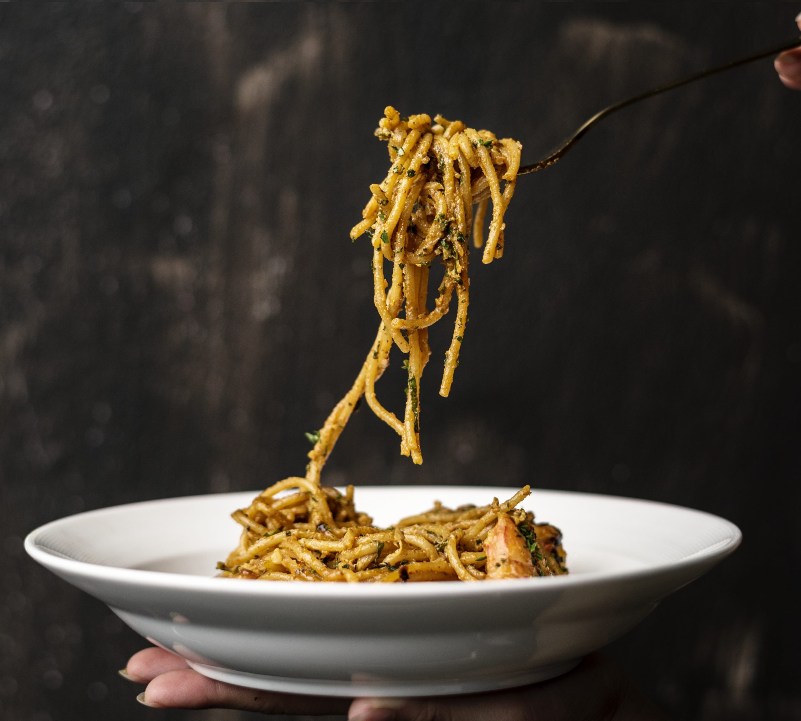 Woman hands holding plate of spaghetti illustrate blog "Where Does Carbonara Come From? (the Answer Will Surprise You)"