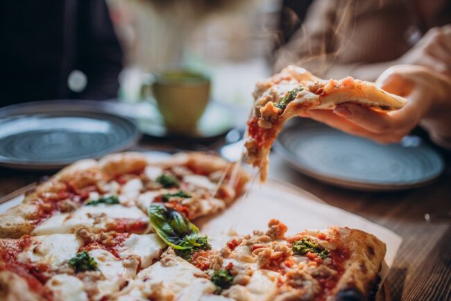 Three firends together eating pizza in a cafe Person holding pizza.