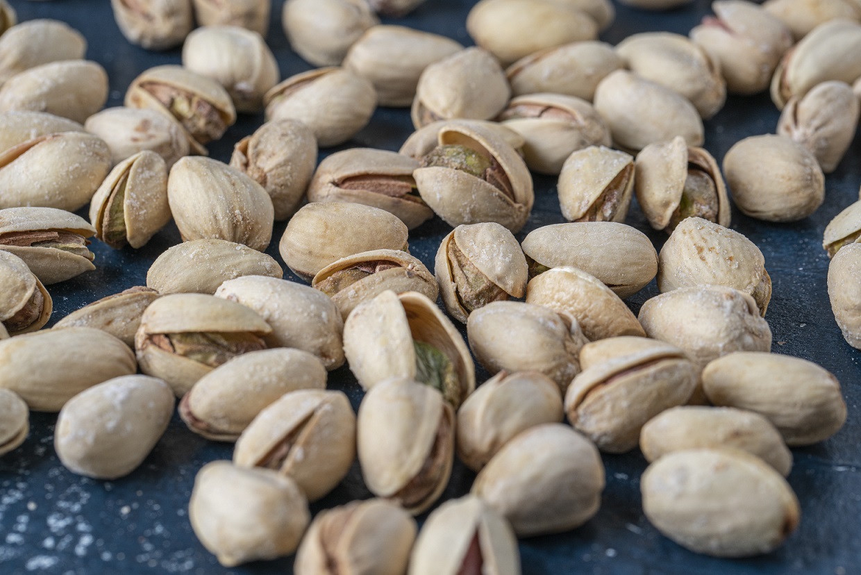 Closeup shot of the pile of delicious roasted and salted pistachios Closeup of pistachios illustrates blog "Are Pistachios Vegan?"